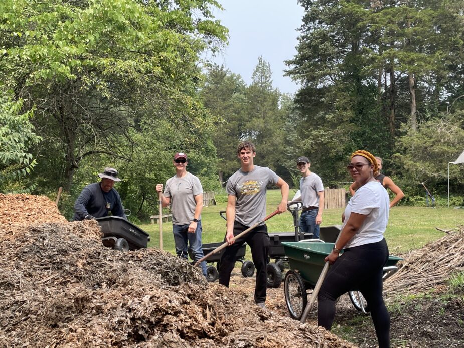AMSG team smiling at the camera while shoveling mulch into wagons.