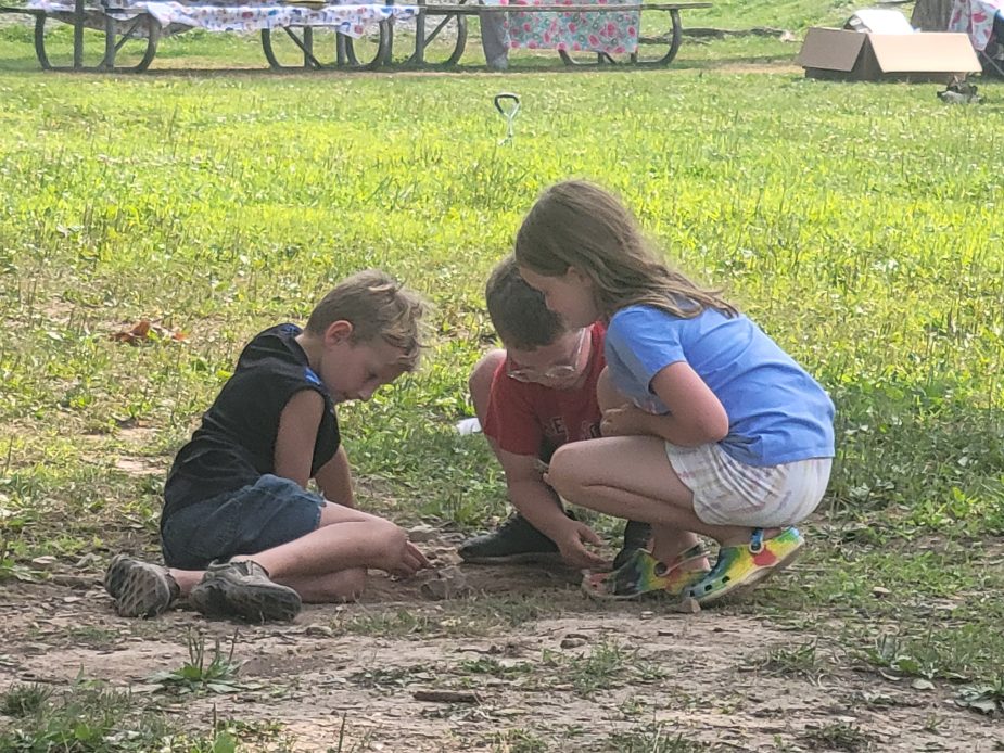 Kids playing with sand in the grass.
