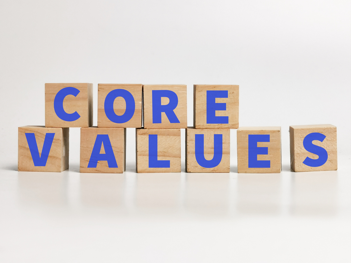 Eight light-colored wooden blocks arranged in two rows, spelling "CORE" on the top row and "VALUES" on the bottom row, with blue letters on each block.