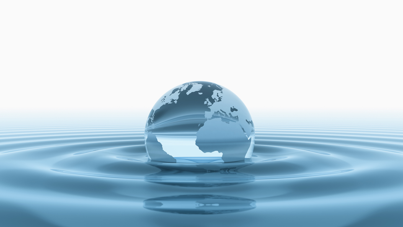 Glass globe with a map of continents partially submerged in water, creating concentric ripples.