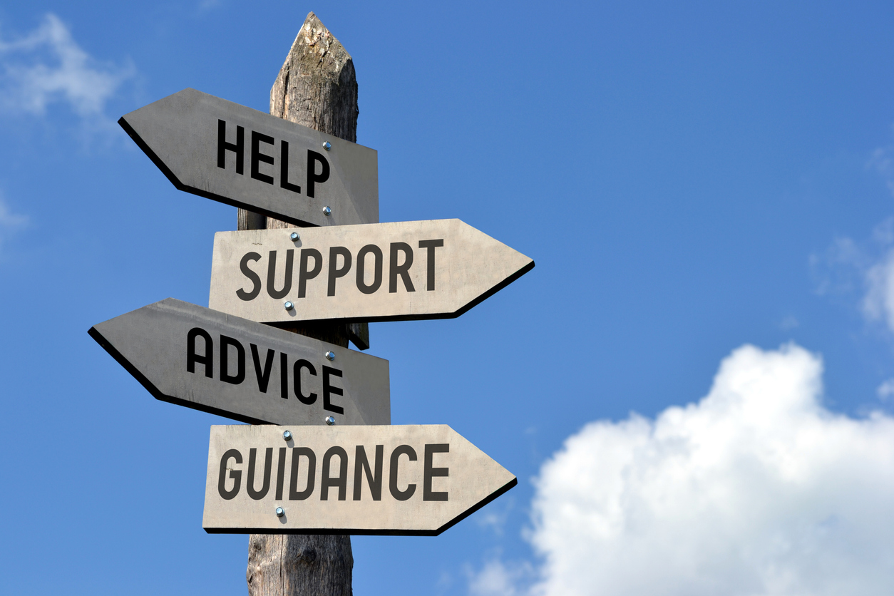 A wooden signpost with four directional arrows pointing to the right, labeled with the words: "Help," "Support," "Advice," and "Guidance."